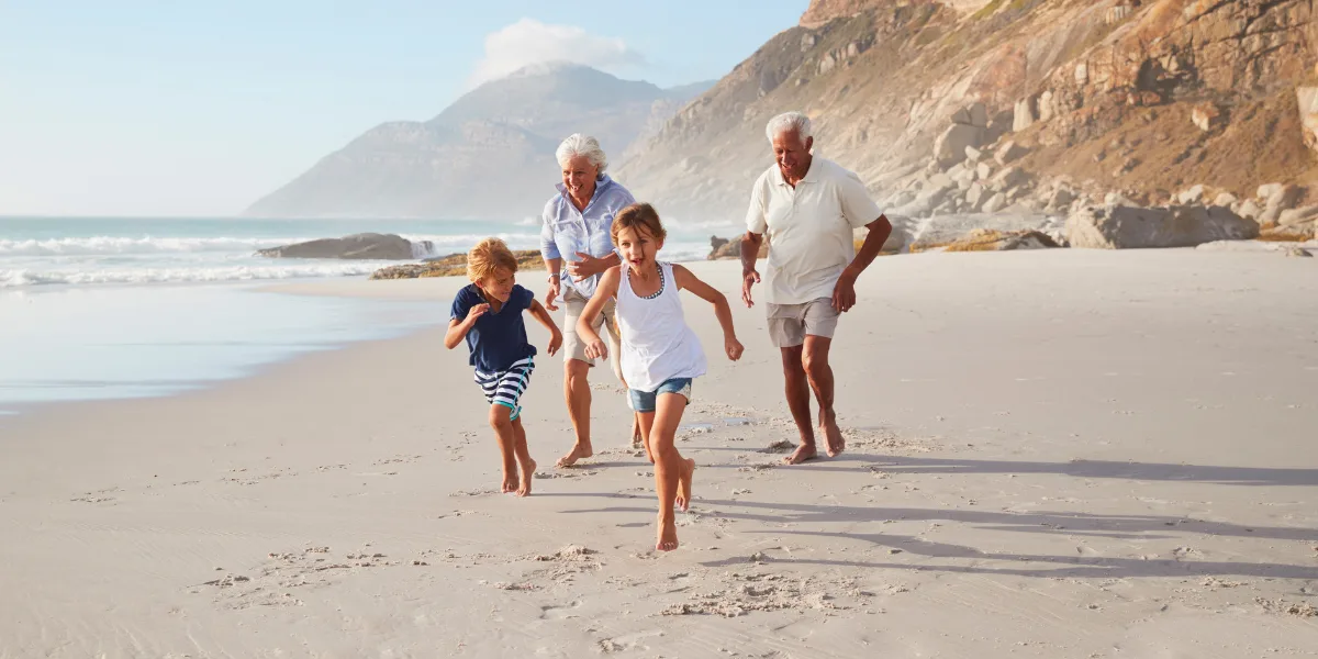 Active grandparents running on the beach with their grandchildren, symbolizing joint comfort and mobility freedom